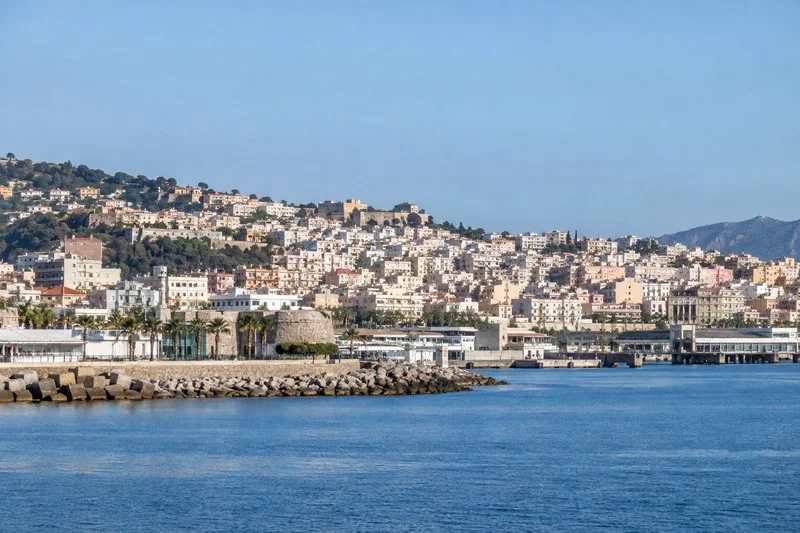 Vista costera de Ceuta con el puerto, el mar y edificios que ascienden por la ladera.